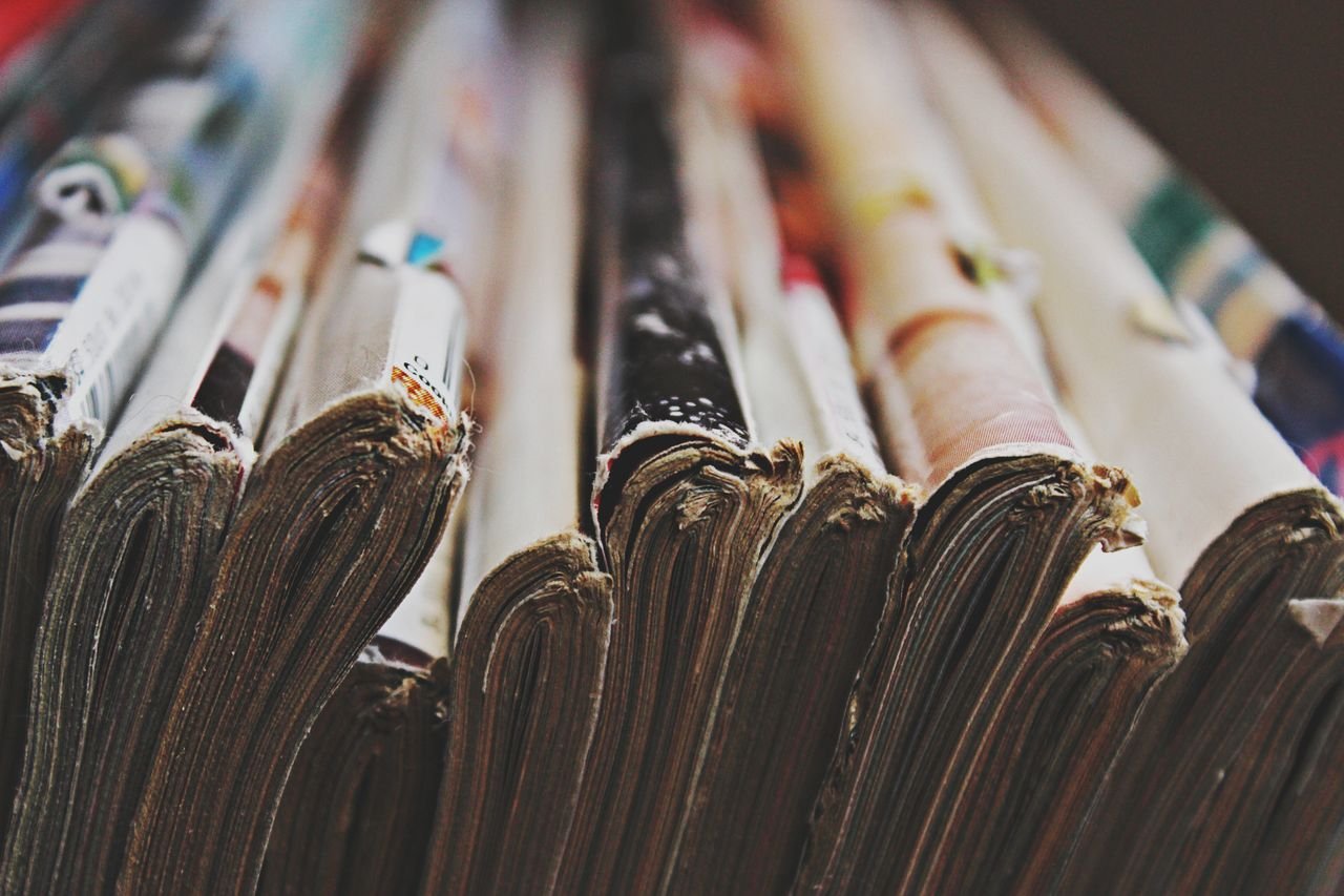 About A detailed close-up image of a stack of magazines arranged in a row, showcasing their bindings.